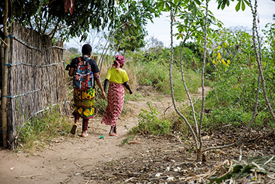 A Vulnerable Lives Survey (VLS) enumerator walking through the neighborhoods of Monapo with a local guide, Nampula Province