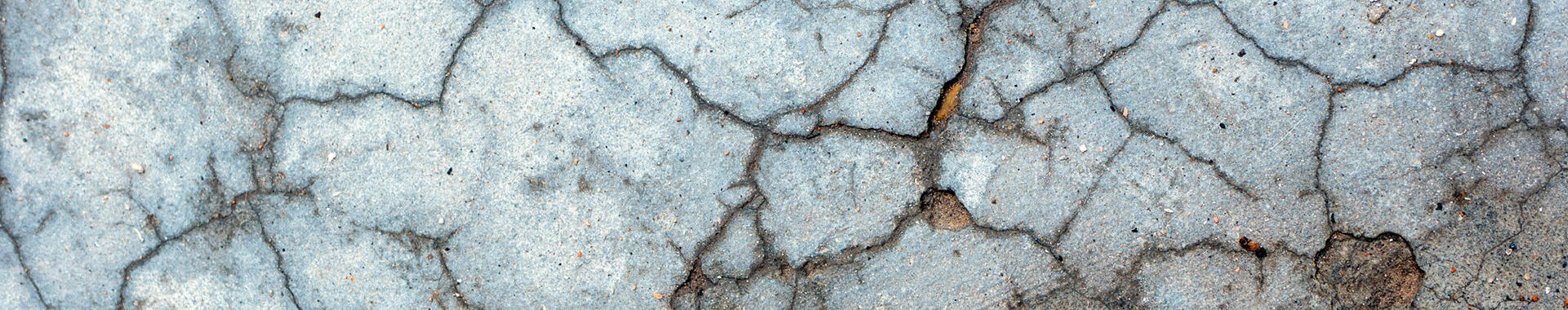 A close-up of a cracked concrete surface. Photo by Daniela Paola Alchapar on Unsplash