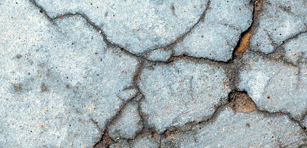 A close-up of a cracked concrete surface. Photo by Daniela Paola Alchapar on Unsplash